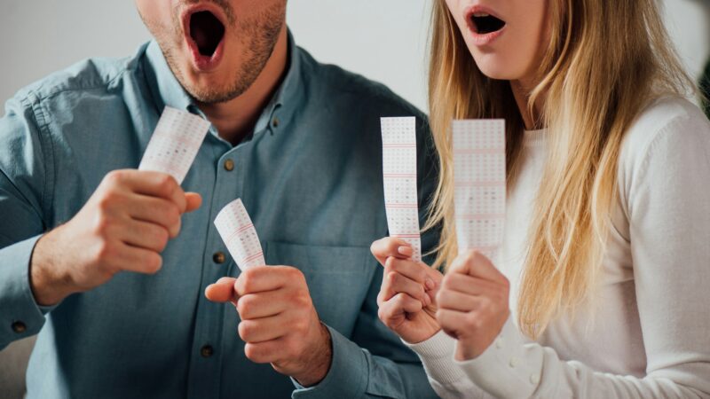 cropped view of shocked man and woman holding lottery tickets